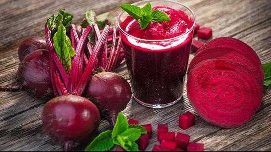 Beetroot benefits: Fresh beetroots, beetroot juice, and sliced beetroot pieces on a wooden table, rich in nutrients for skin, hair, and health.